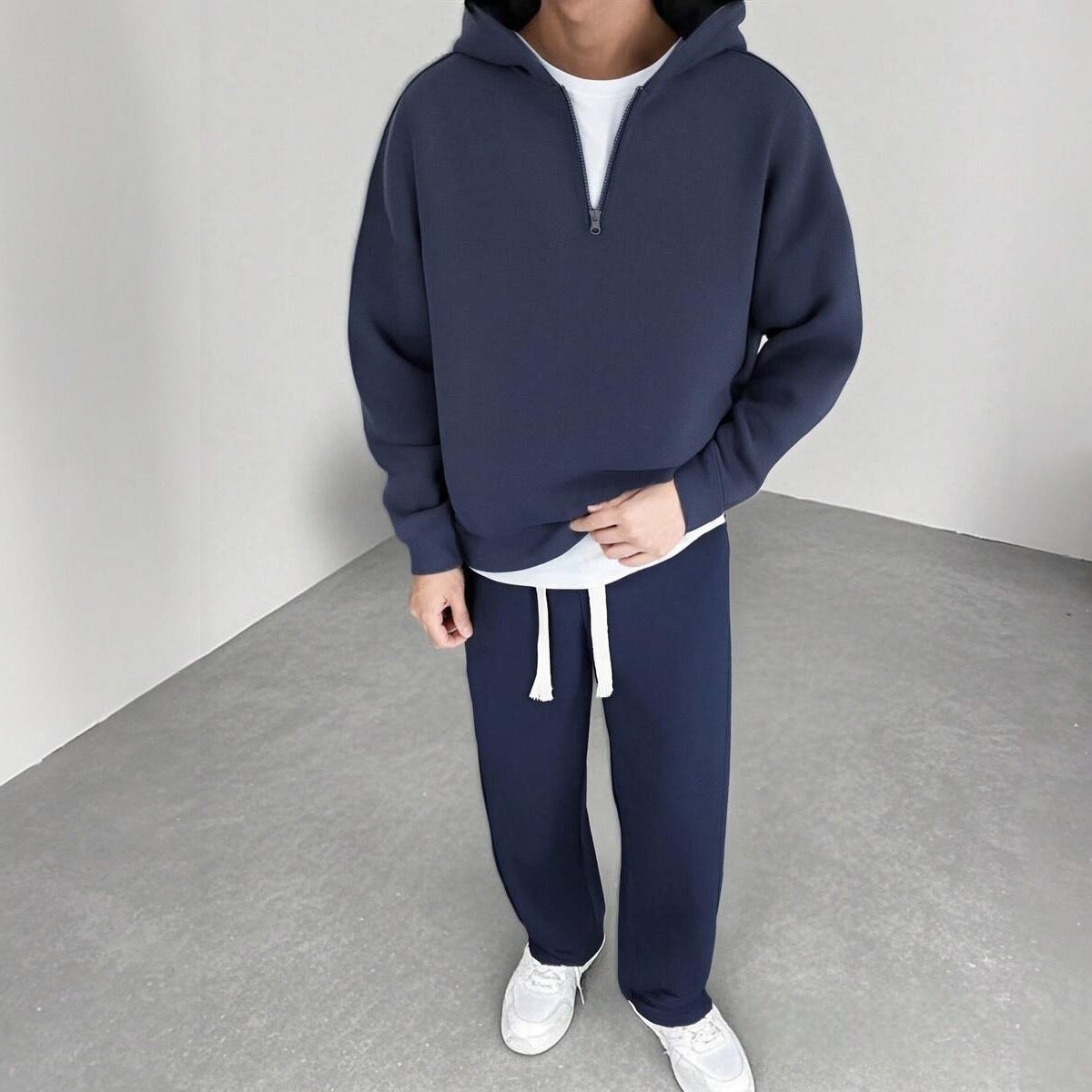 Man draagt marineblauw joggingpak met halfzip hoodie en wijde broek | Boutique Moda