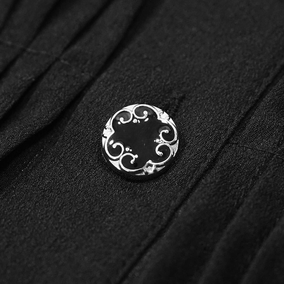 Zilverkleurige sierknoop met krullend ornament op zwarte geplooide stof | Boutique Moda