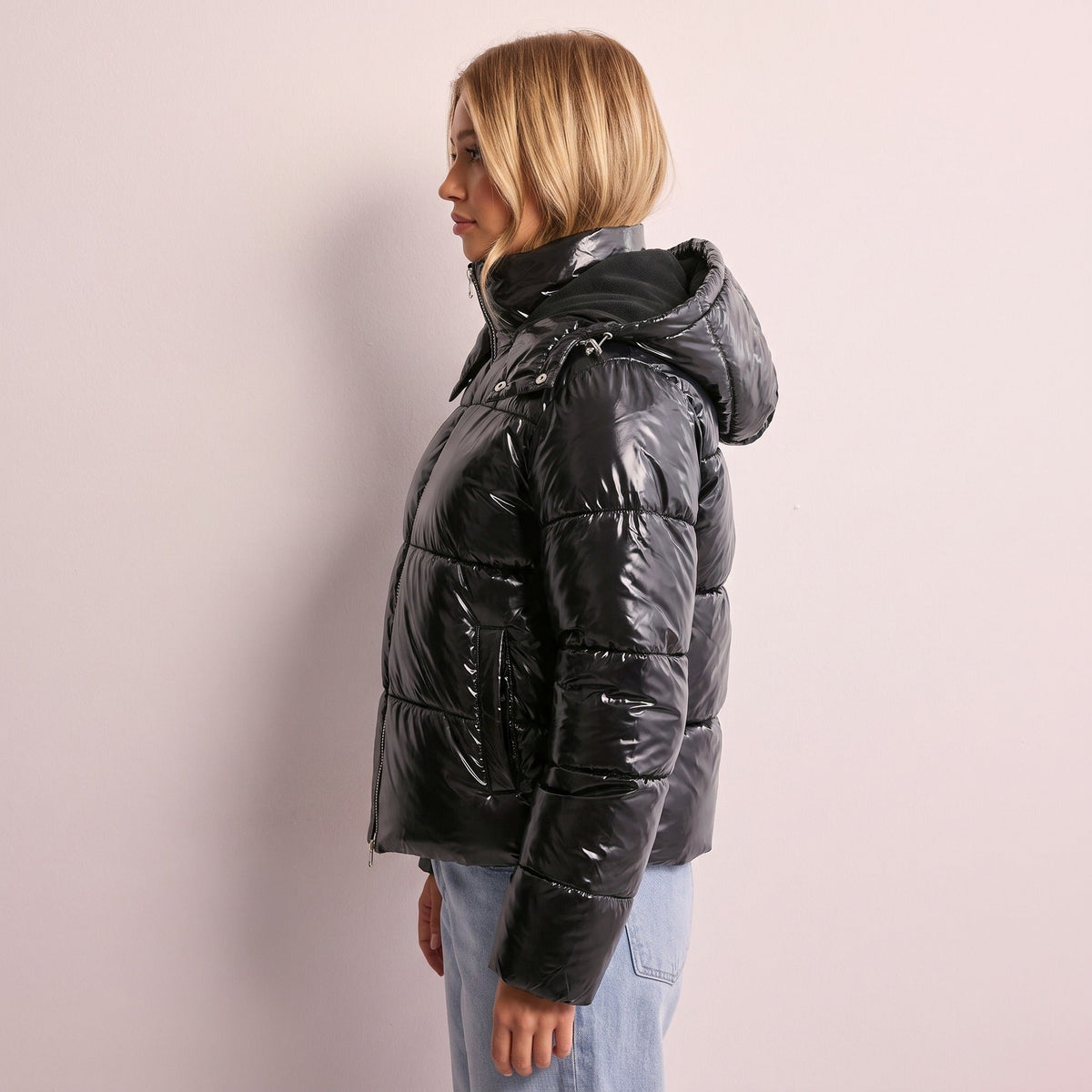 Glanzende zwarte gewatteerde jas met capuchon, gedragen door vrouw | Boutique Moda