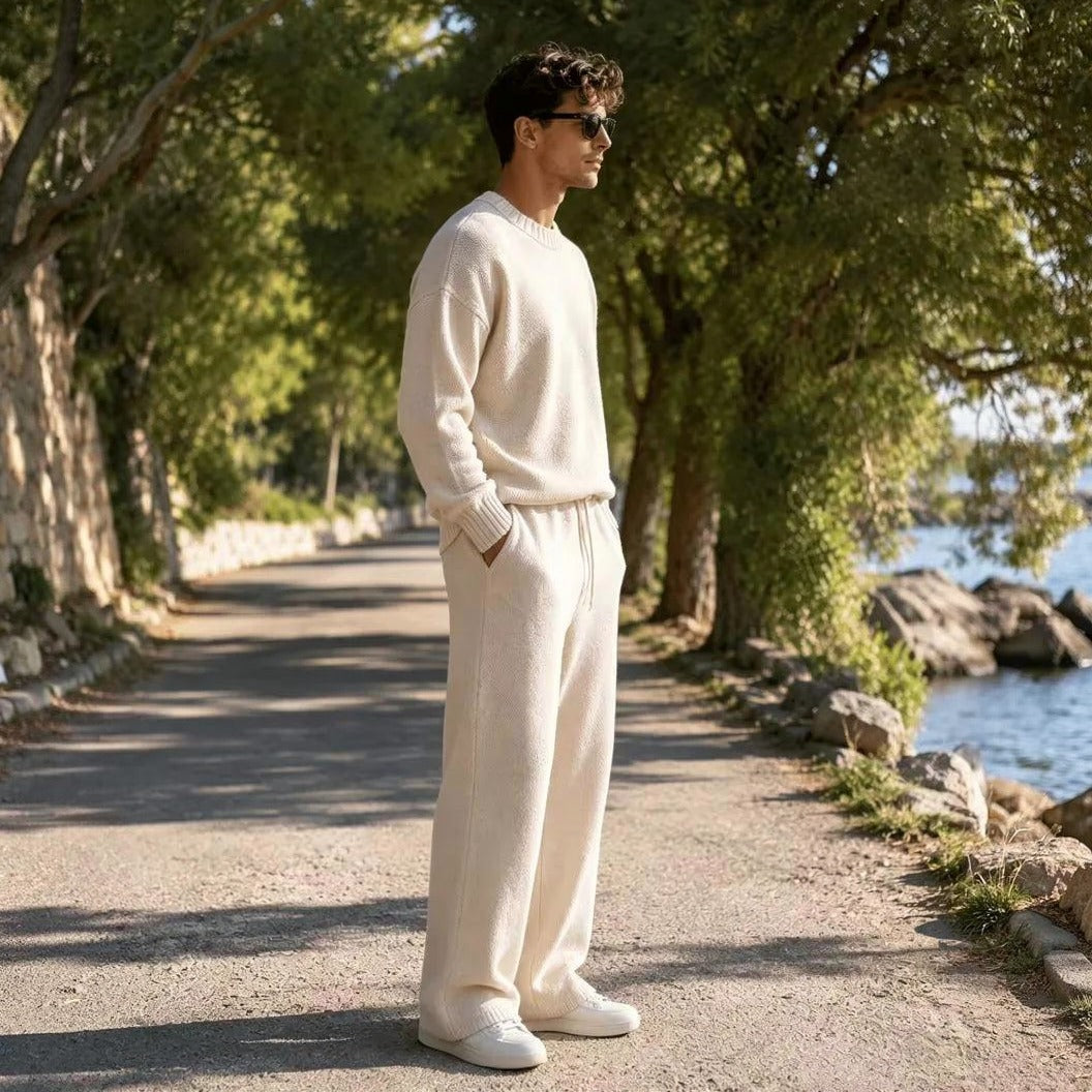 Man draagt crème gebreide oversized trui en wijde broek buiten | Boutique Moda