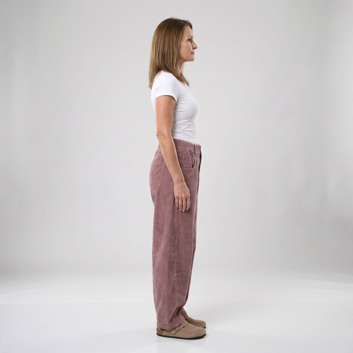Vrouw draagt wijde corduroy broek in oudroze, zijaanzicht, witte achtergrond | Boutique Moda