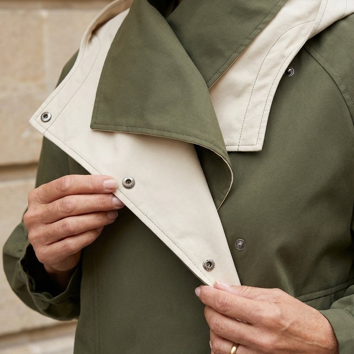 Groene regenjas met beige binnenvoering en drukknopen, gedragen door persoon | Boutique Moda