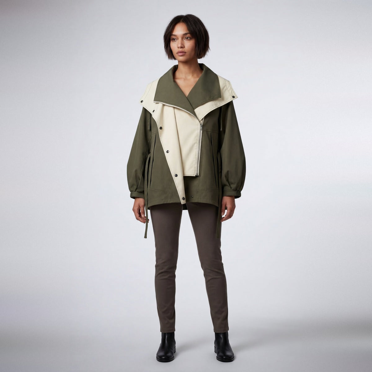Groen-beige regenjas met capuchon gedragen door vrouw met bruine broek | Boutique Moda