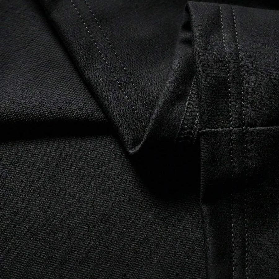 Close-up van zwarte stof met stiksels en mouwdetail, plat gefotografeerd | Boutique Moda