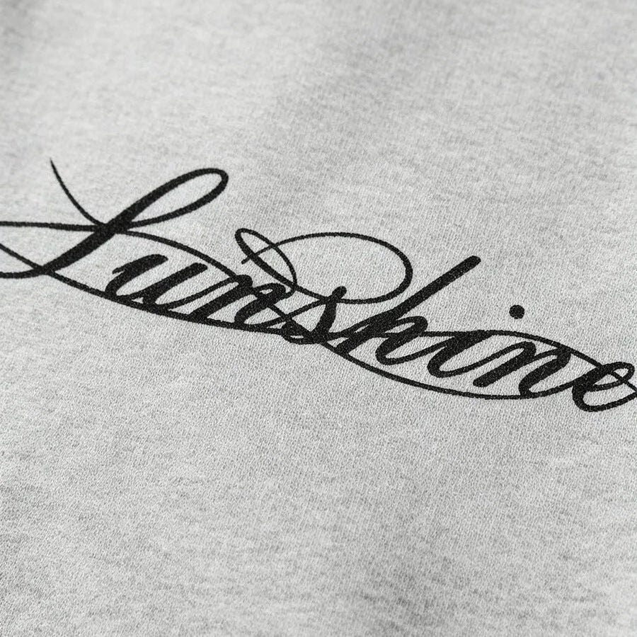 Close-up van grijze longsleeve met zwarte cursieve tekst, textuur zichtbaar | Boutique Moda