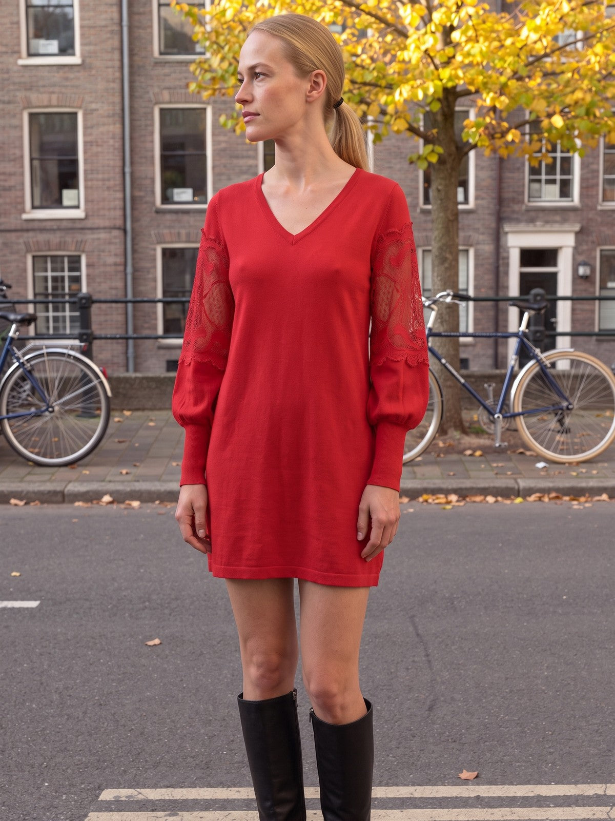 Vrouw in de rode mini jurk met kanten mouwen in een Amsterdamse straat