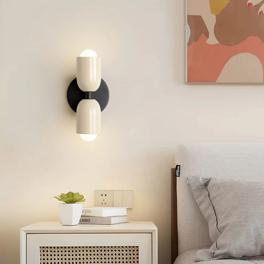 Crème dubbele wandlamp brandend naast het bed, licht valt omhoog en omlaag langs de muur | Boutique Moda