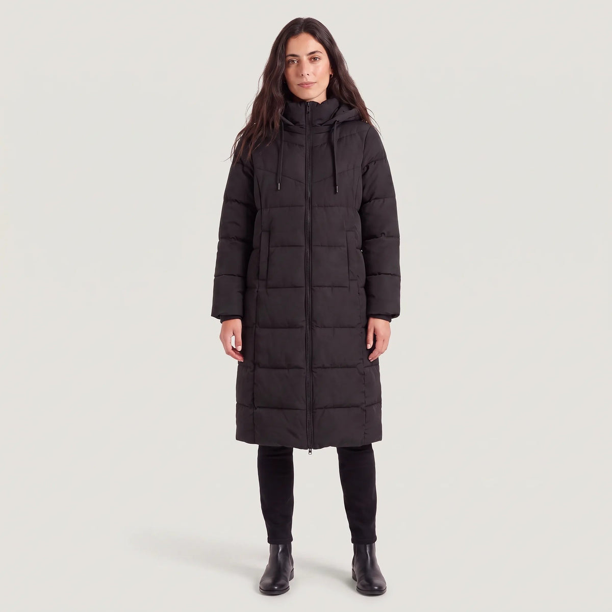 Vrouw in een lange zwarte pufferjas met capuchon