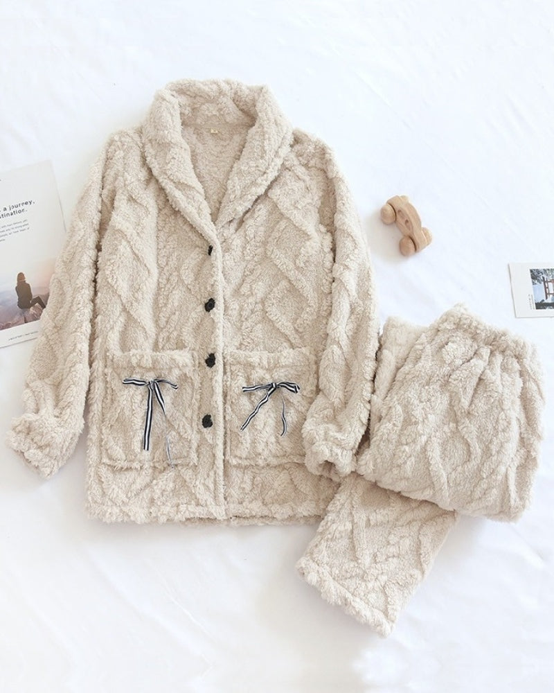 Crèmekleurige fleece pyjama met sjaalkraag, knoopsluiting en zakken met strik, plat neergelegd
