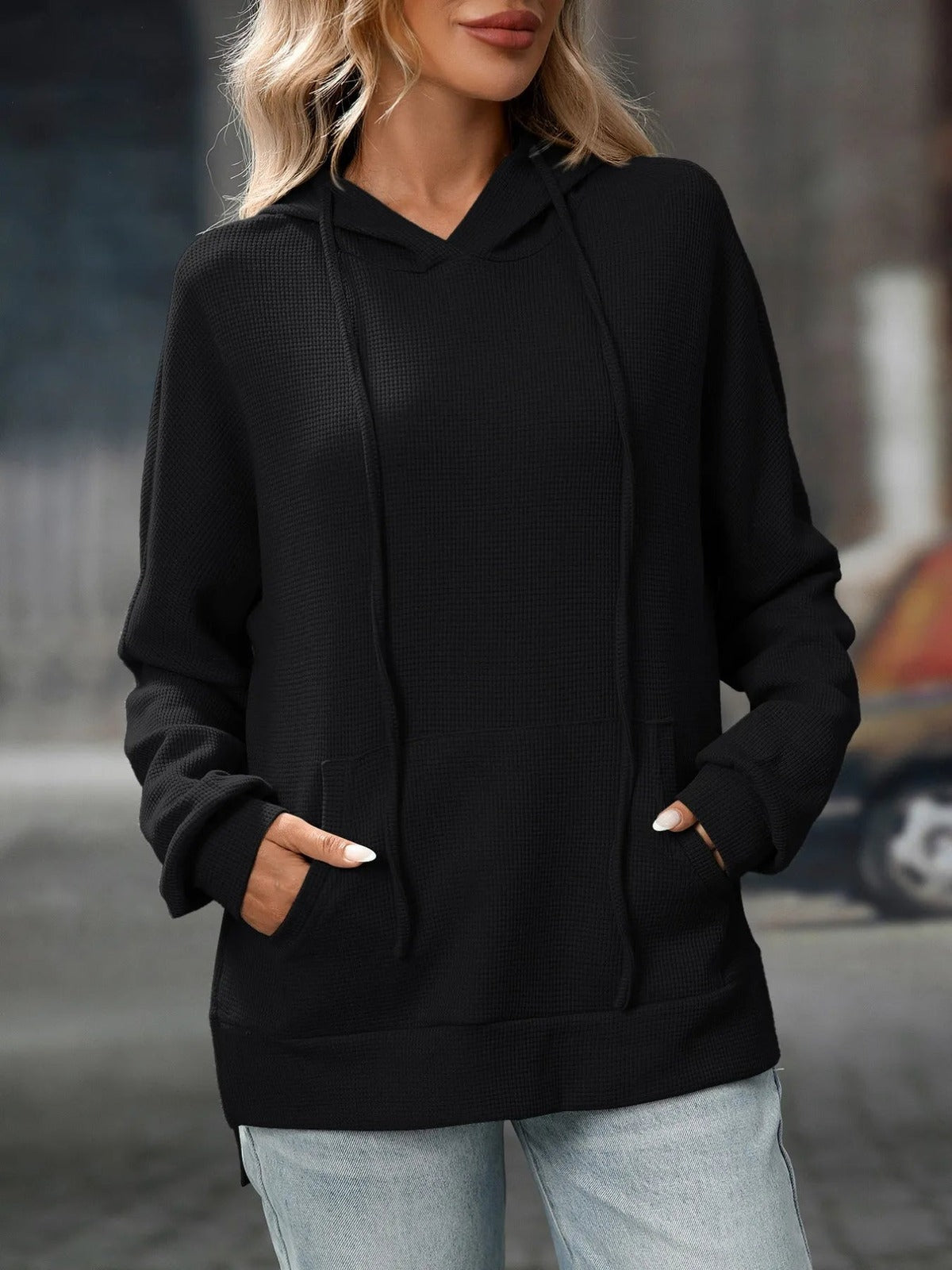 Zwarte sweater met capuchon en wafelstructuur, gedragen met lichte jeans | Boutique Moda