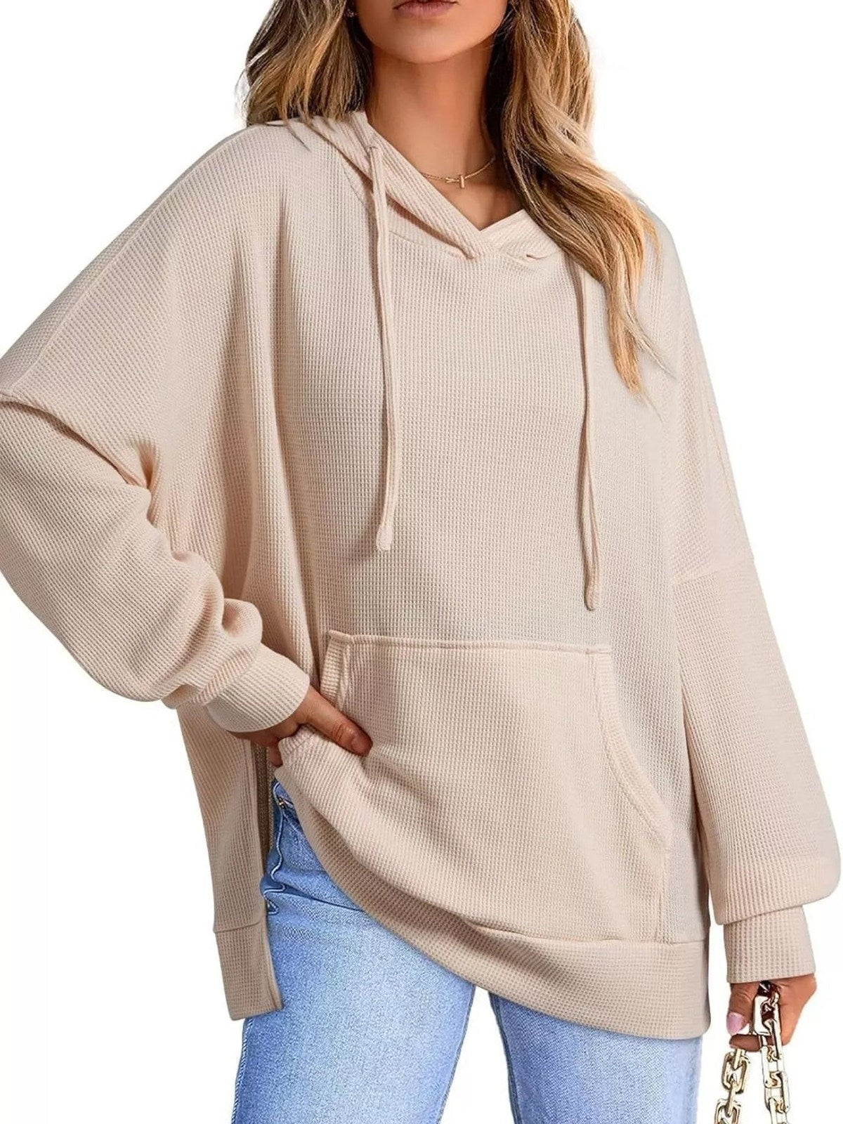 Vrouw in beige oversized capuchontrui met wafelstructuur en lichte jeans | Boutique Moda