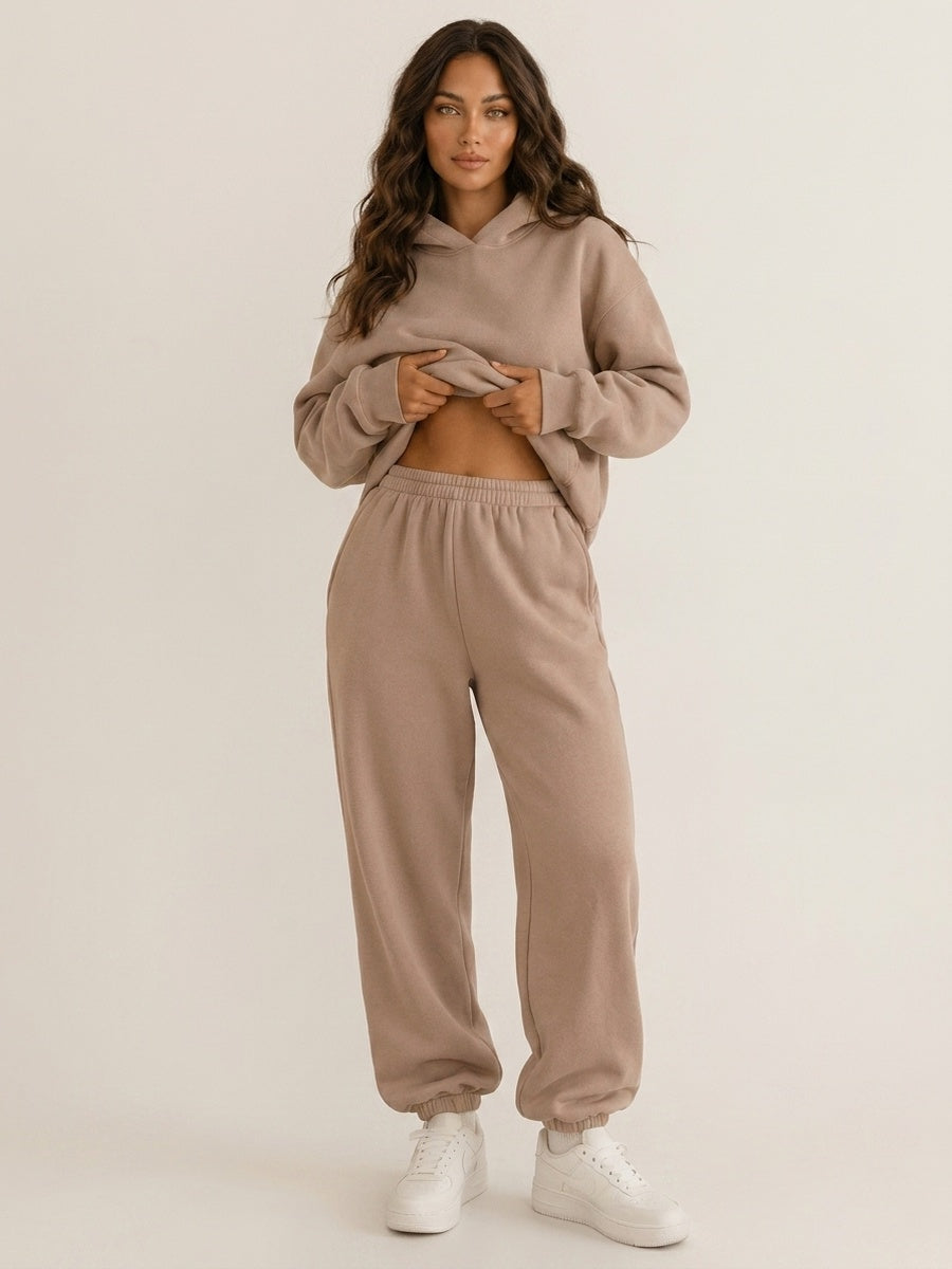 Taupe joggingpak, hoodie opgetild zodat de elastische tailleband te zien is