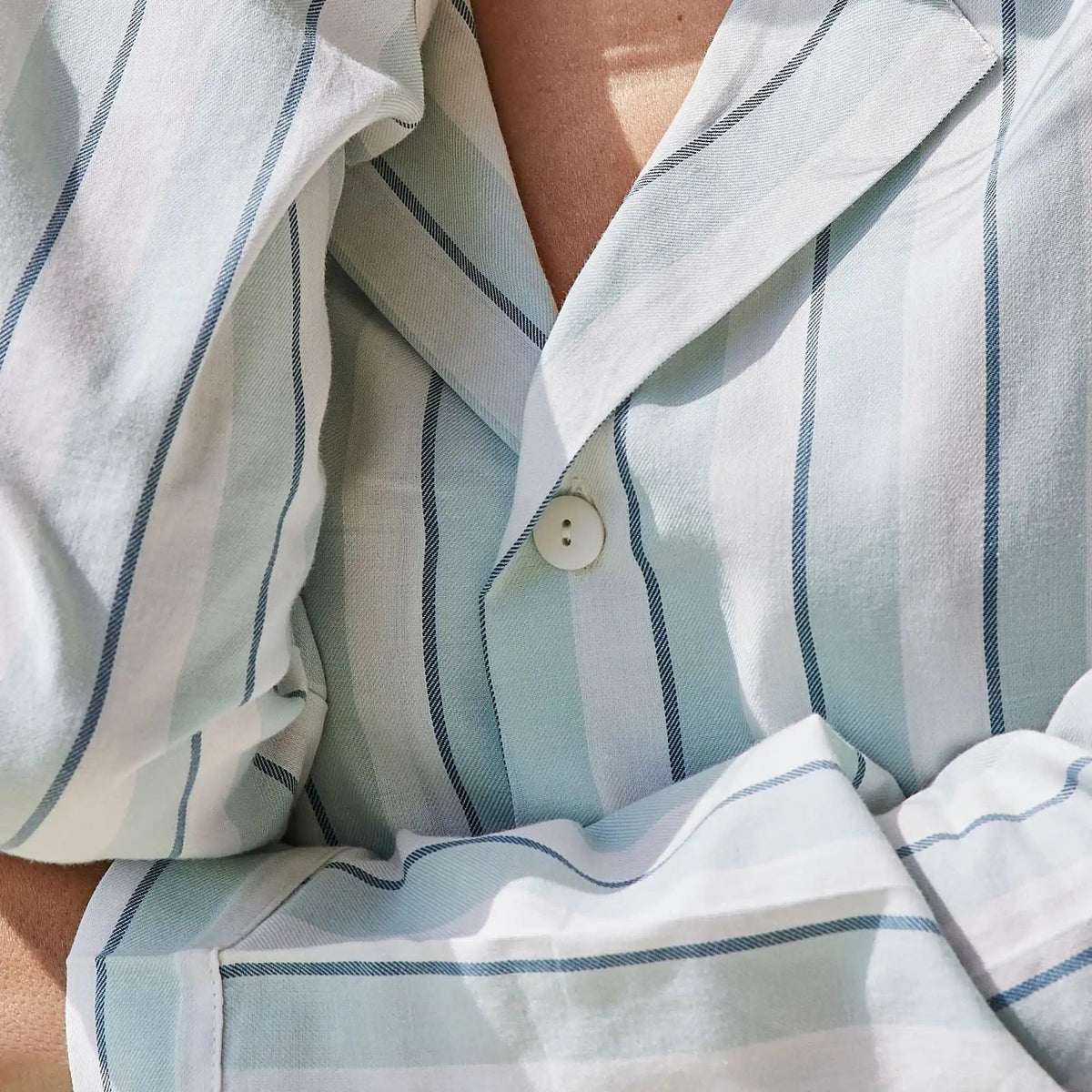 Gestreept katoenen pyjamashirt in wit met saliegroene en blauwe strepen, close-up van de kraag en knopen