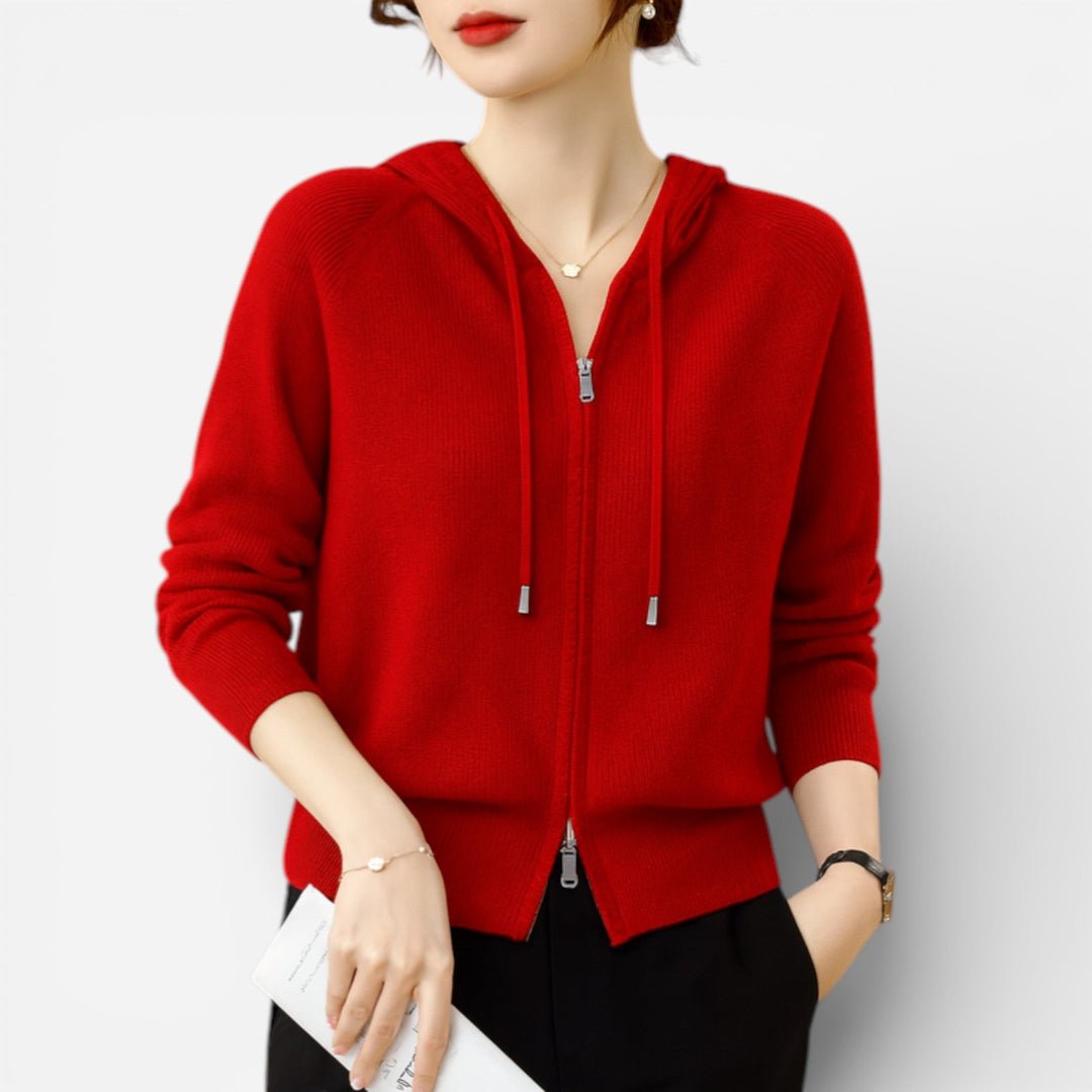 Vrouw draagt een rood gebreid vest met capuchon en dubbele rits, met een zwarte broek | Boutique Moda