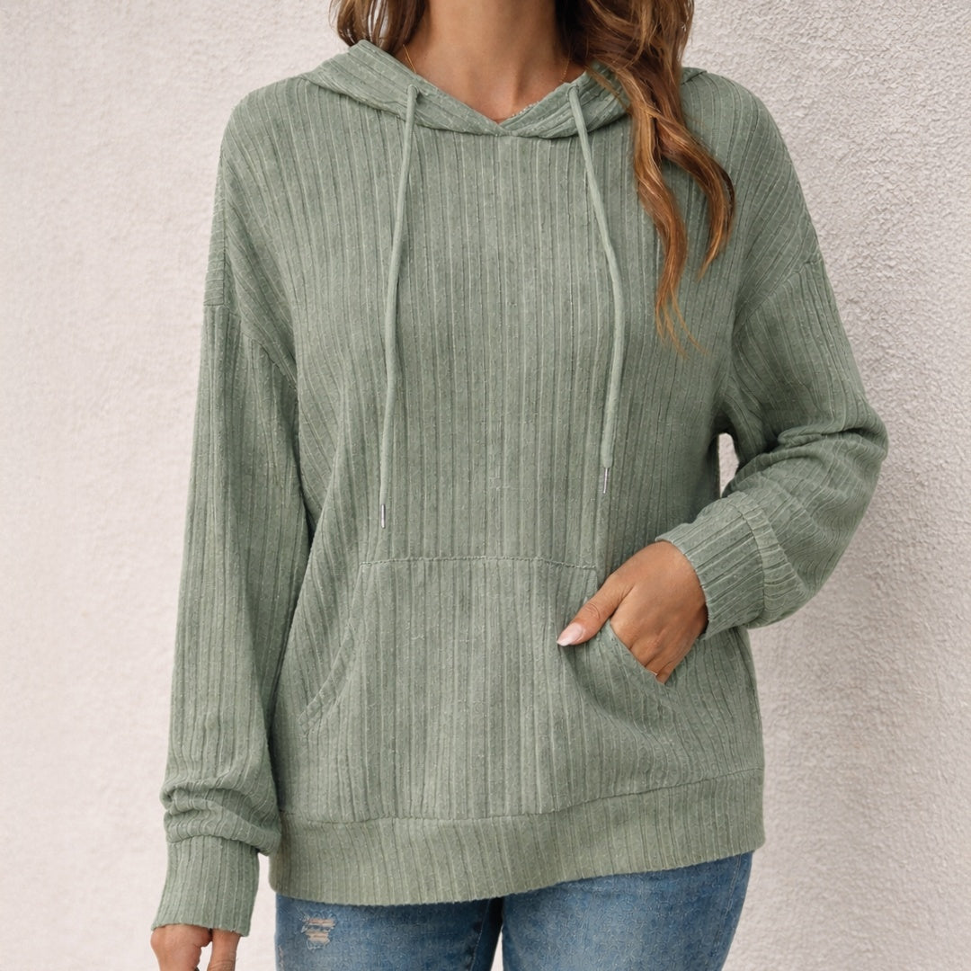 Vrouw in een saliegroene hoodie met koorden en brede zoomband, met een jeans | Boutique Moda