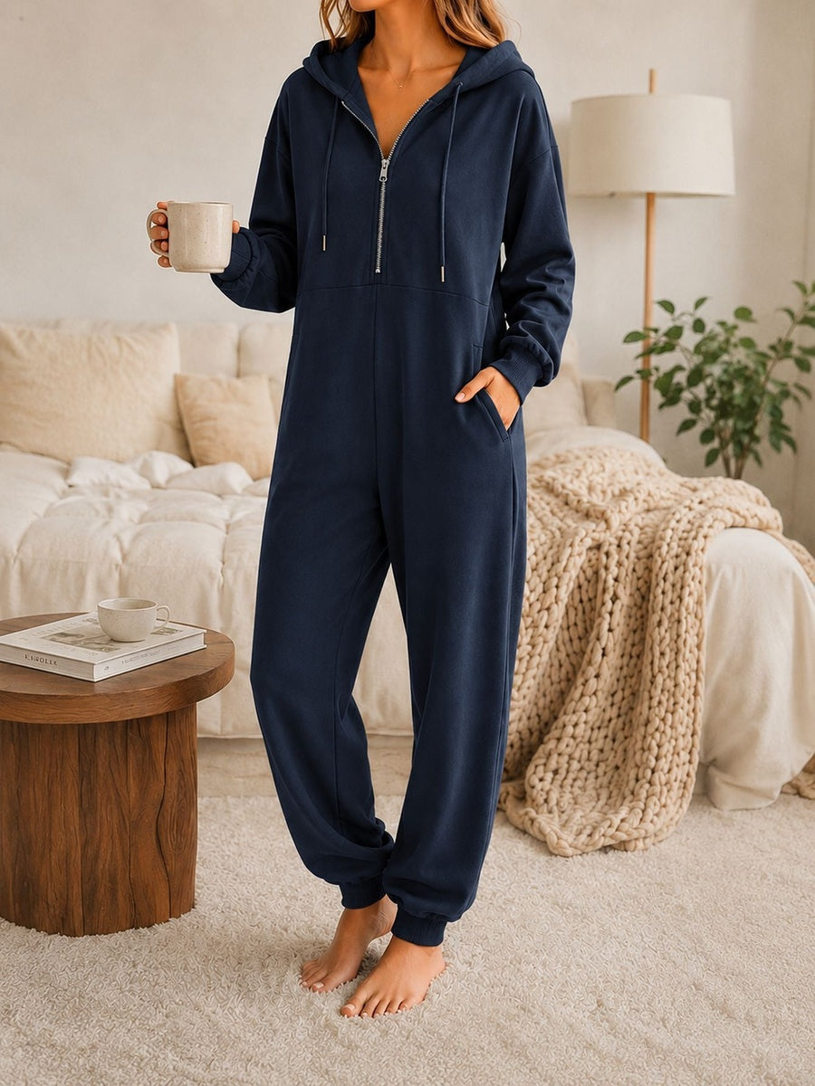 Onesie met capuchon in marineblauw met halve rits en zakken opzij, vooraanzicht in de slaapkamer