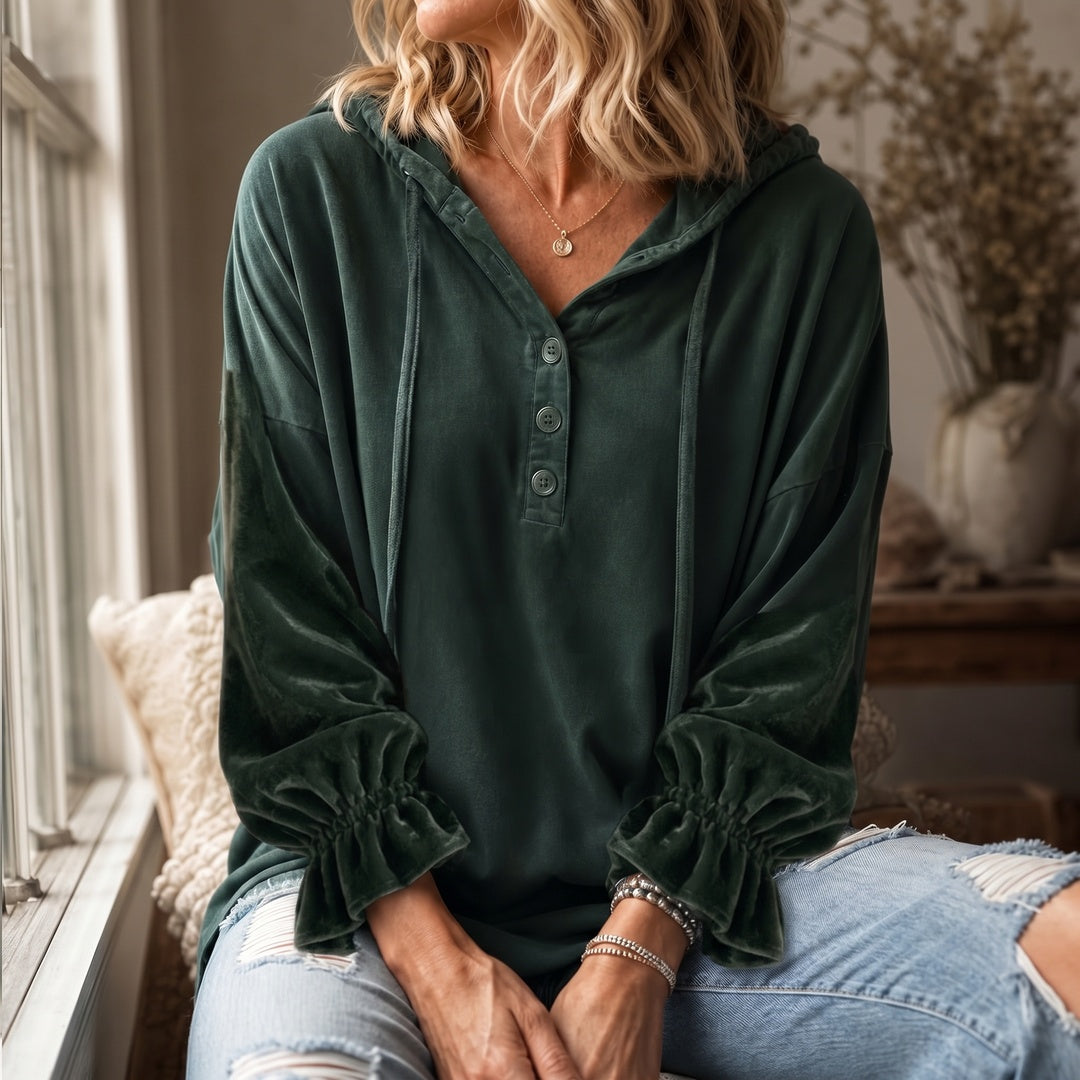 Vrouw in een donkergroene hoodie bij het raam, met ruches aan de ballonmouwen | Boutique Moda