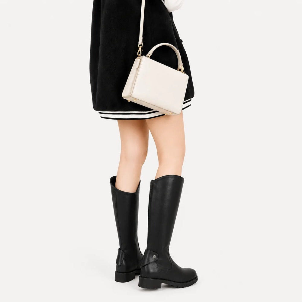 Zwarte rijlaarzen gedragen met een minirok
