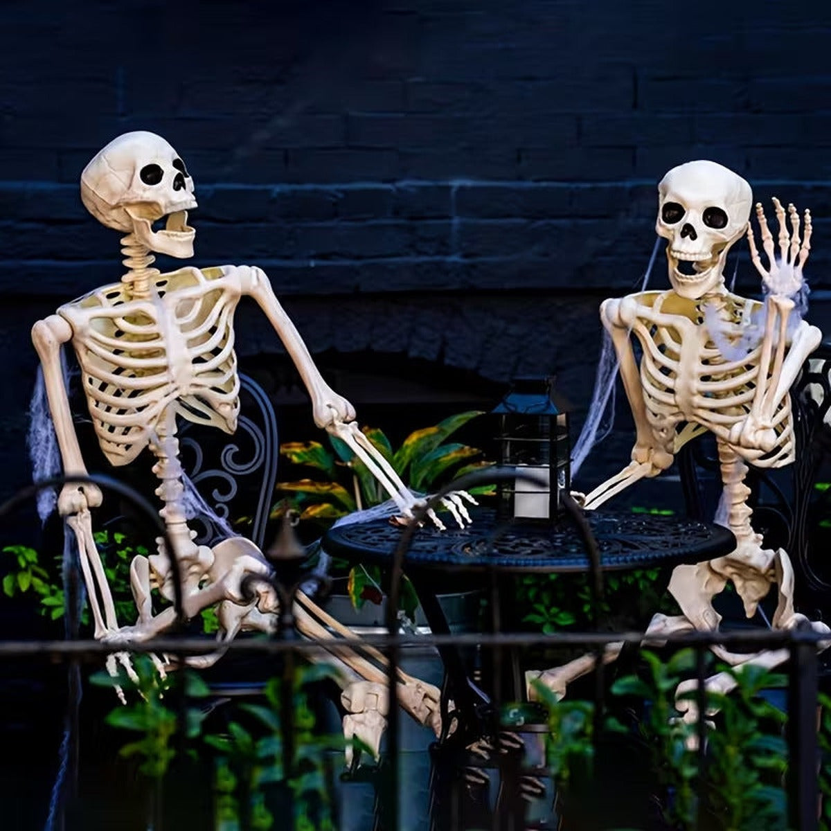 Twee skeletten aan een tuintafel als decoratie voor Halloween