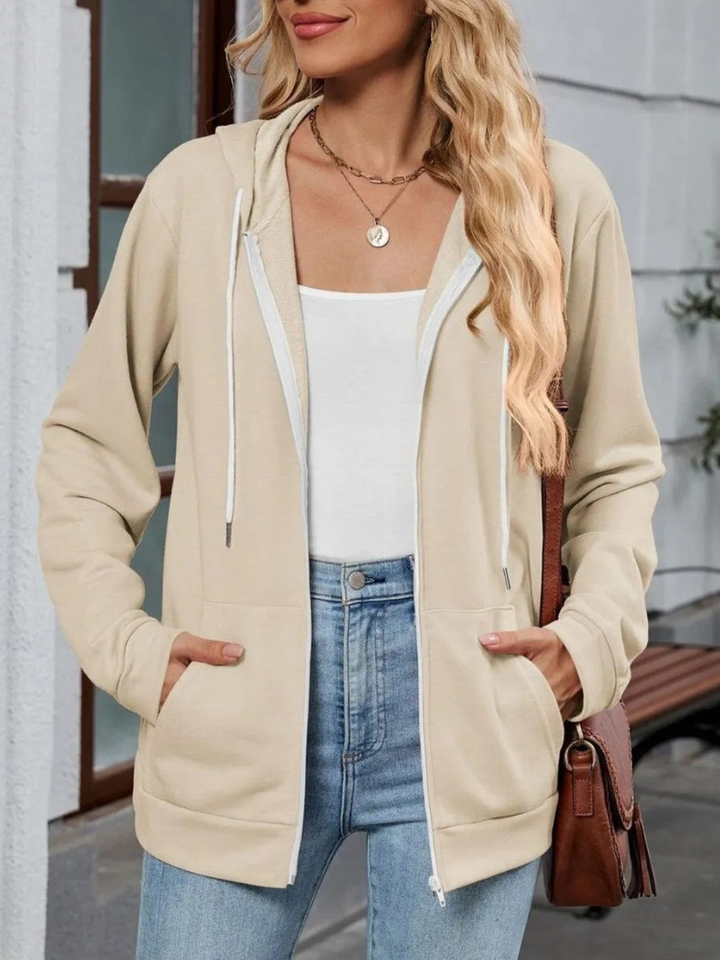 Vrouw draagt open beige capuchonvest met rits en witte koorden | Boutique Moda