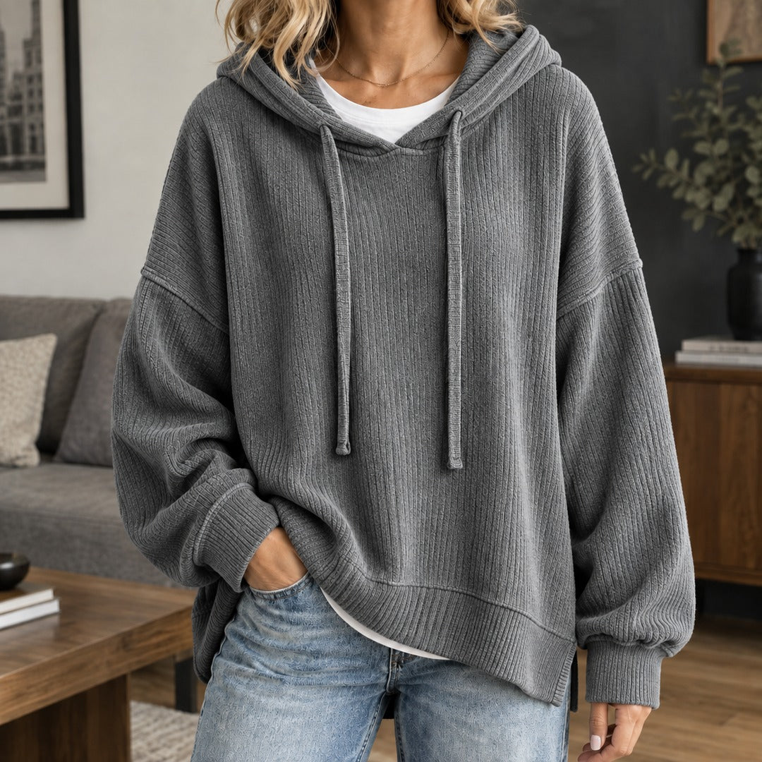 Vrouw in een grijze gebreide trui met wijde mouwen en brede zoomband, met een jeans | Boutique Moda