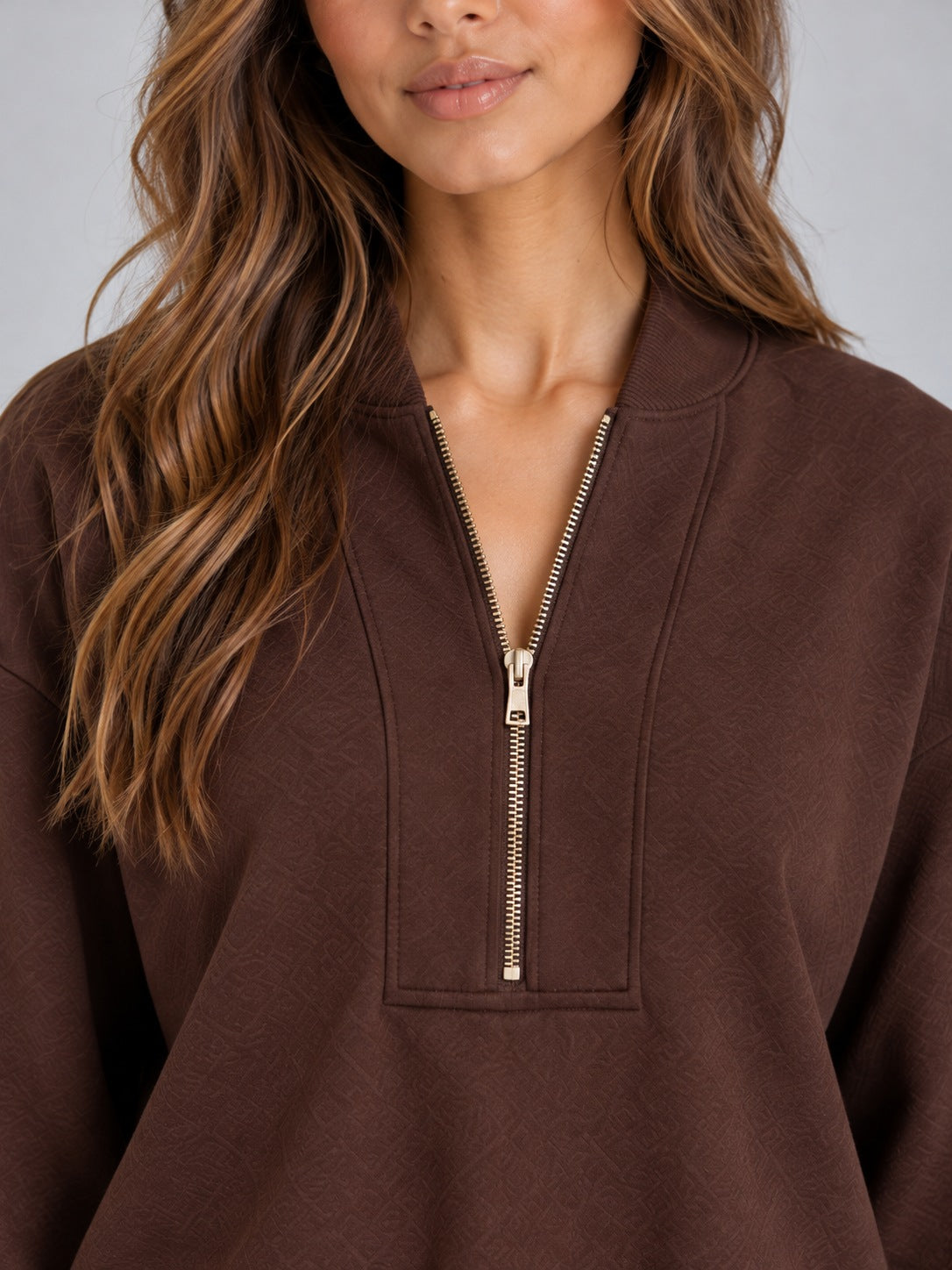 Gebreide tweedelige set met halfzip-trui en wijde broek in bruin, close-up van de halsopening met halve rits