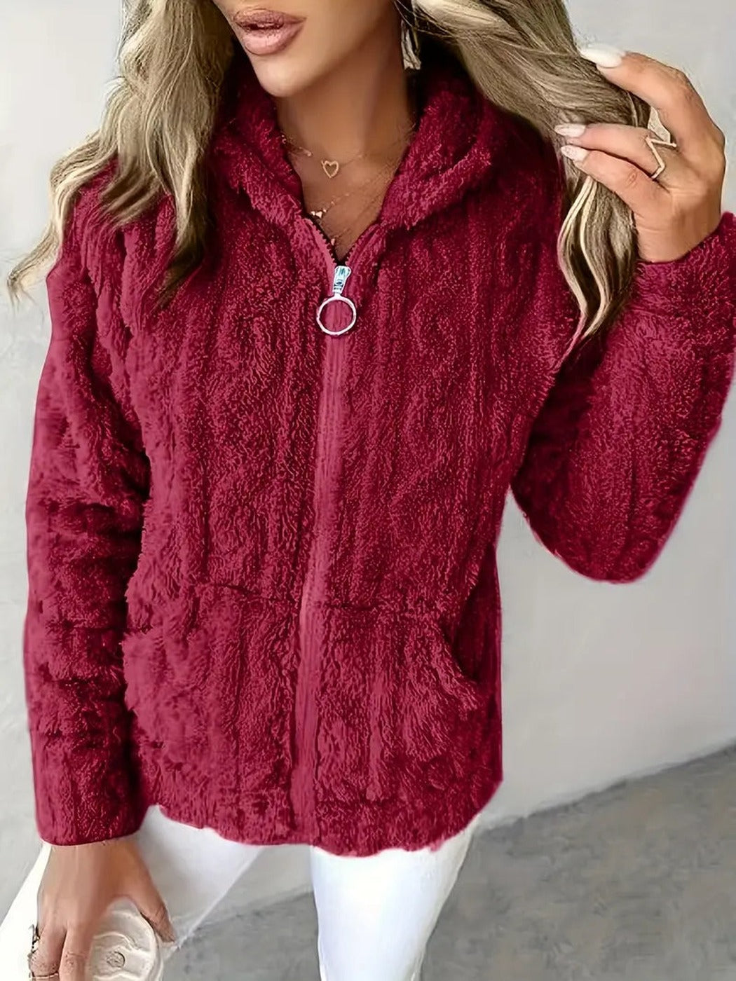 Vrouw draagt een bordeauxrood teddyvest met ringtrekker en twee zakken | Boutique Moda