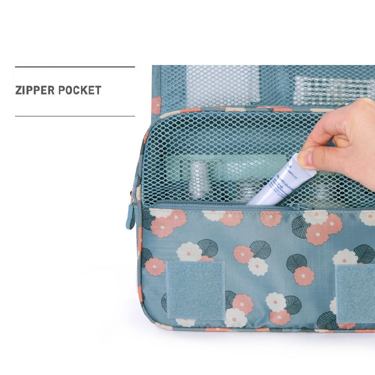 Blauwgroene toilettas met bloemenprint, hand haalt tube uit ritsvak | Boutique Moda