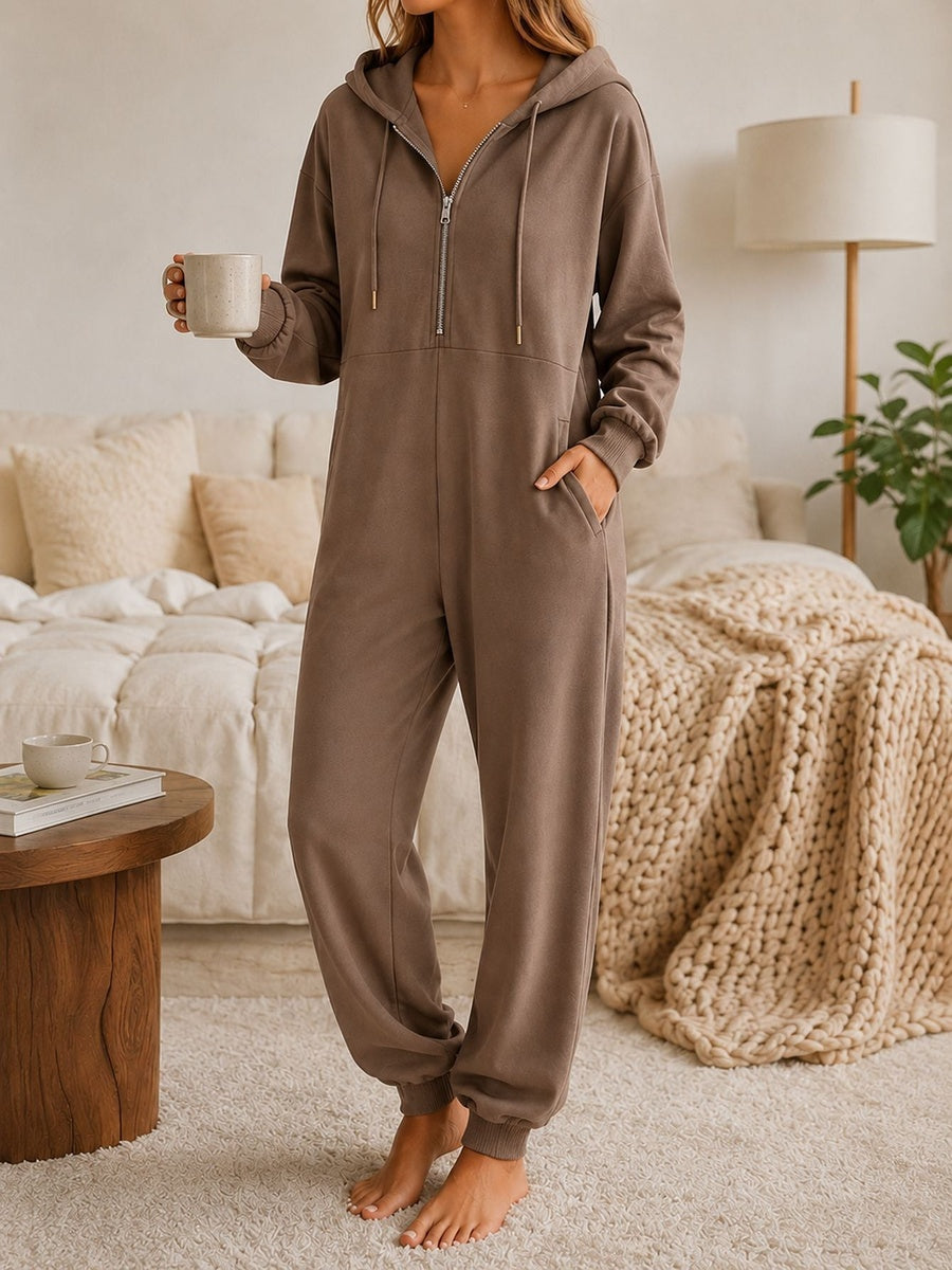 Onesie met capuchon in mokka met halve rits en zakken opzij, vooraanzicht in de slaapkamer