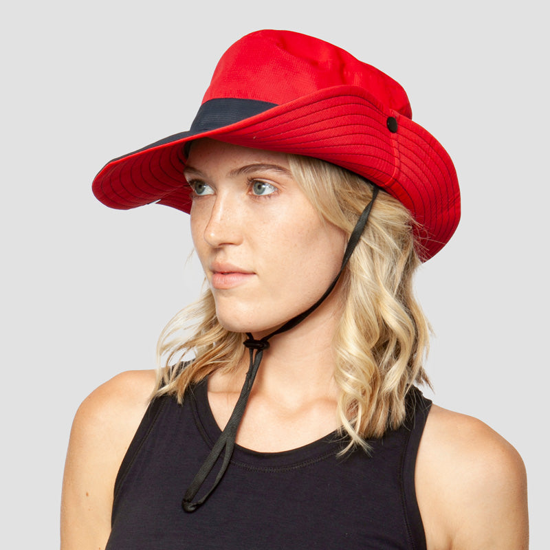 Rode brede-rand zonnehoed met kinband, gedragen door vrouw met blond haar | Boutique Moda