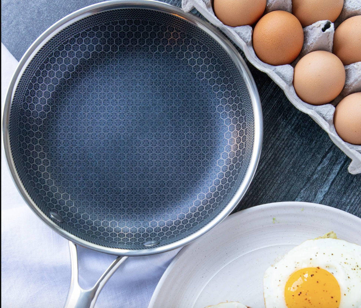 Zilveren koekenpan met honingraatpatroon, plat, naast eieren en gebakken ei | Boutique Moda