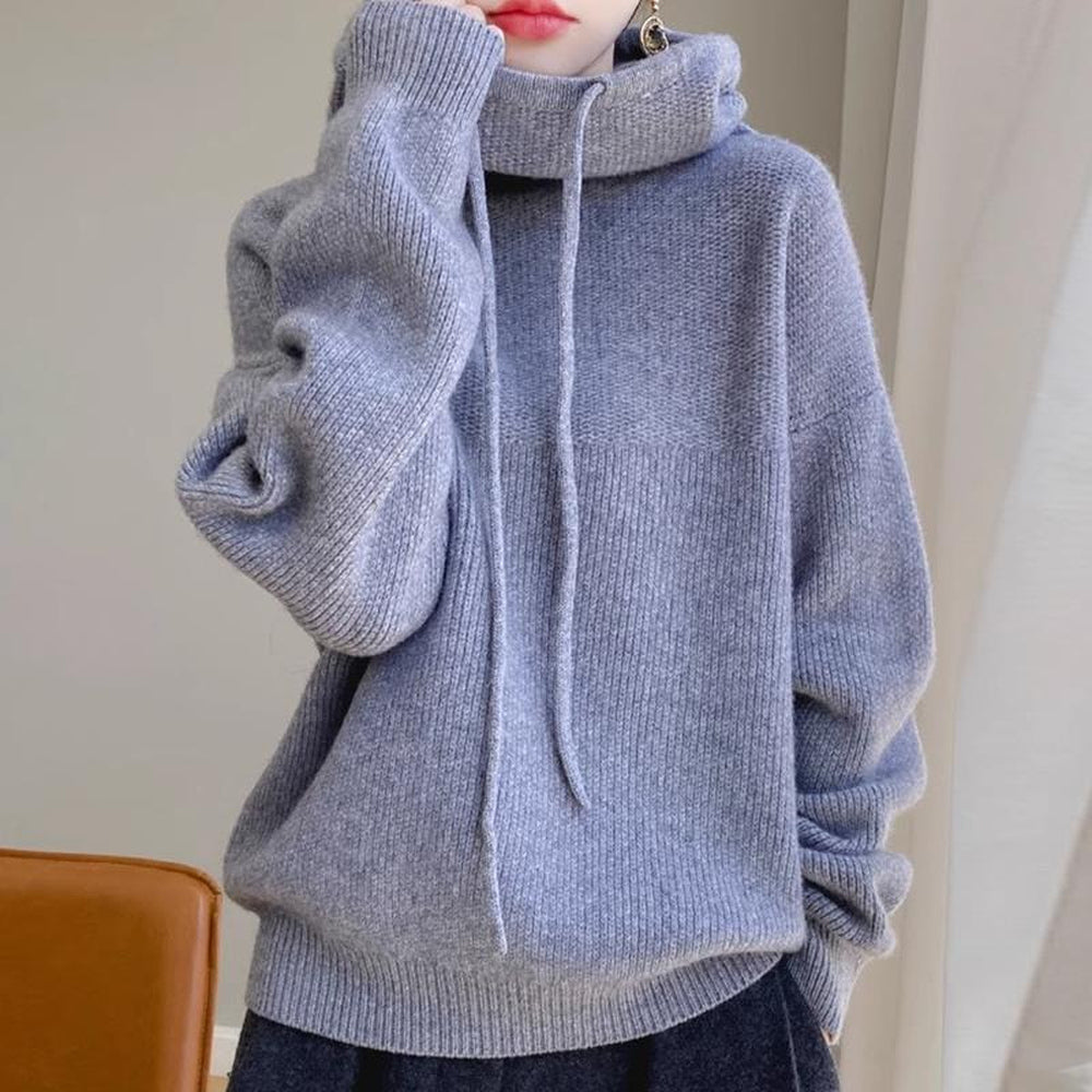 Vrouw in een blauwgrijze gebreide trui met hoge kraag en een donkere broek | Boutique Moda