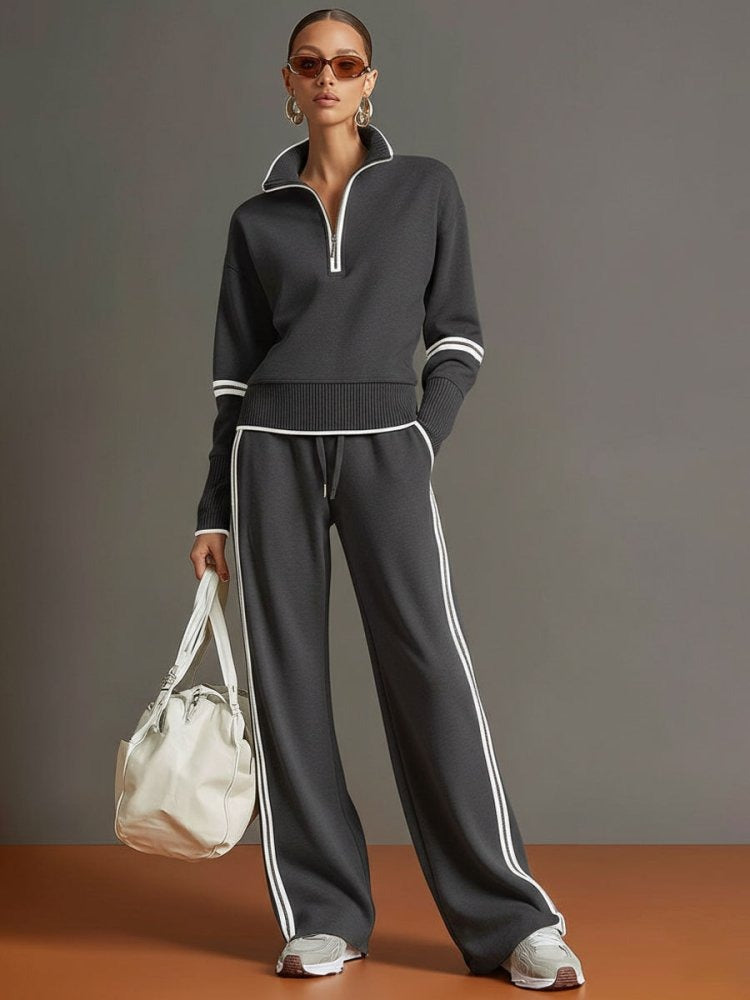 Grijs trainingspak met halve rits en witte streepdetails, gedragen door model | Boutique Moda