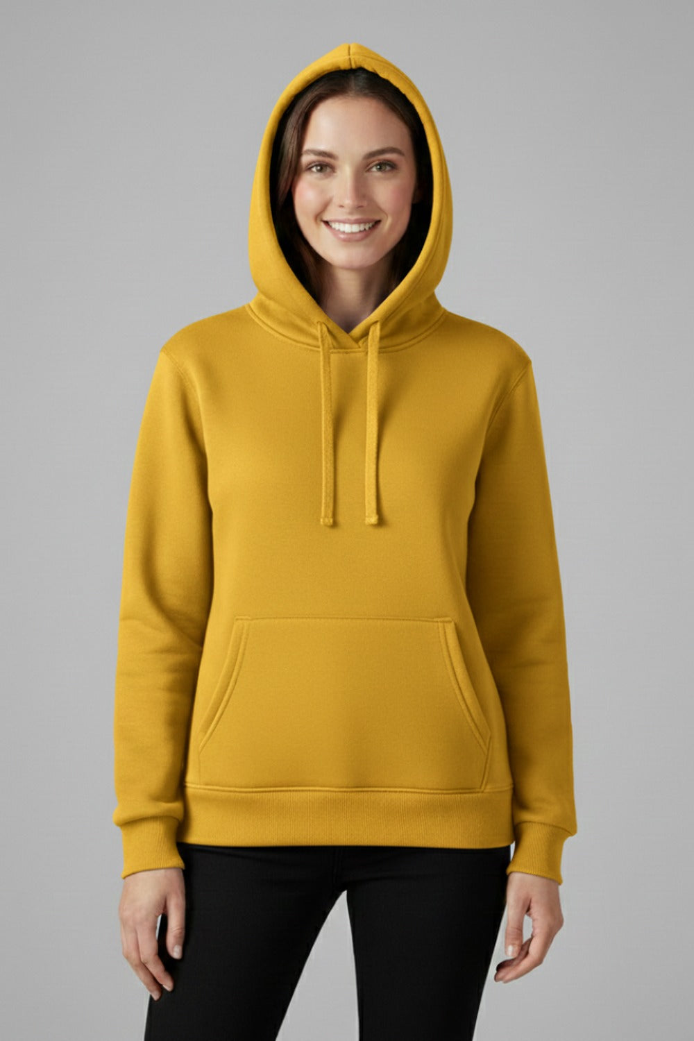 Vrouw in een mosterdgele basic hoodie met capuchon en koorden, met een zwarte broek | Boutique Moda