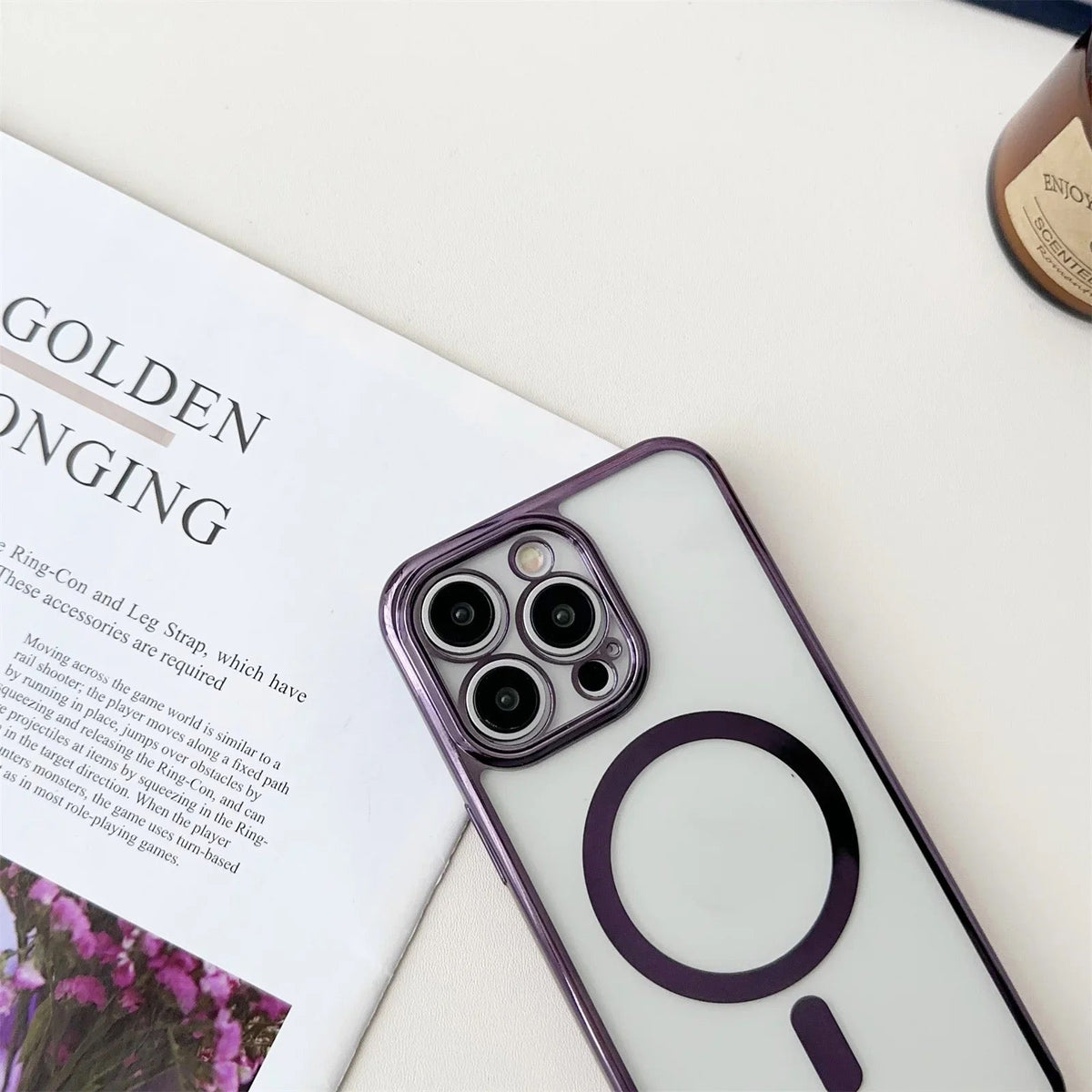 Doorzichtig telefoonhoesje met paarse rand en magnetische ring, plat naast tijdschrift | Boutique Moda