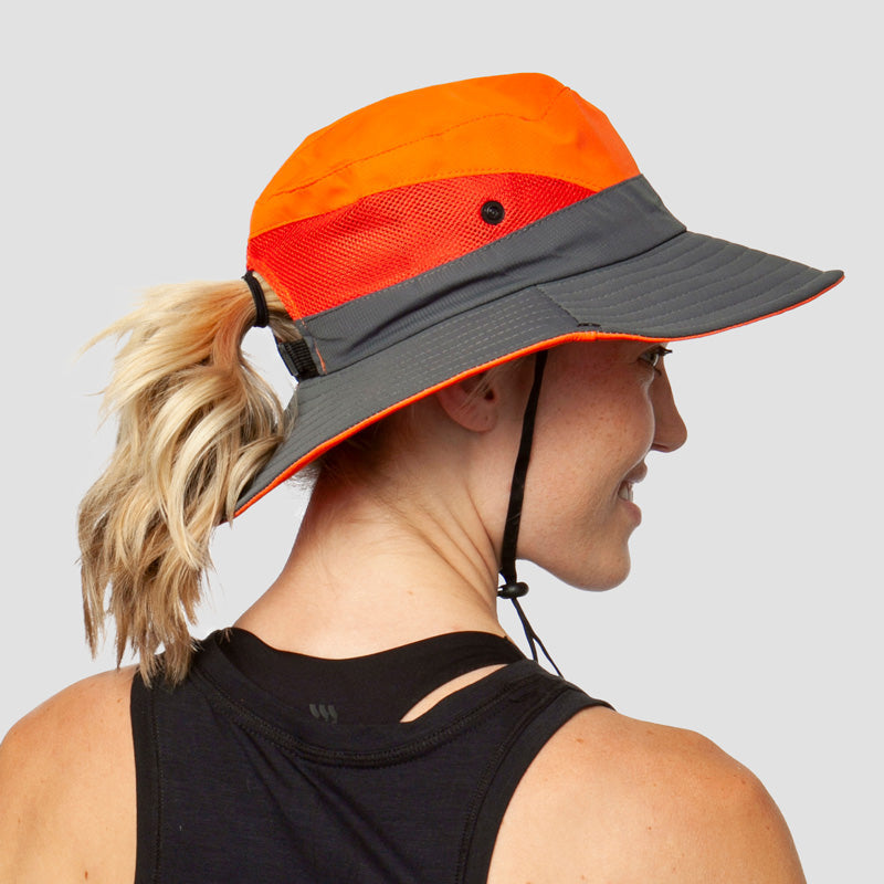 Oranje-grijze opvouwbare zonnehoed met paardenstaartopening, gedragen door blonde vrouw | Boutique Moda