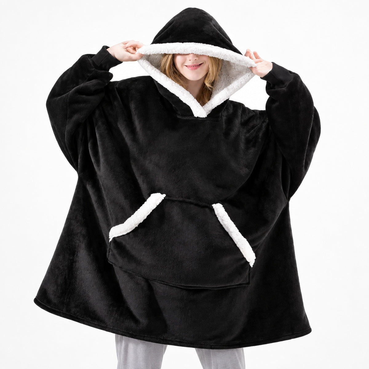 Zwarte oversized hoodie deken met capuchon gedragen door persoon, witte sherpa voering | Boutique Moda
