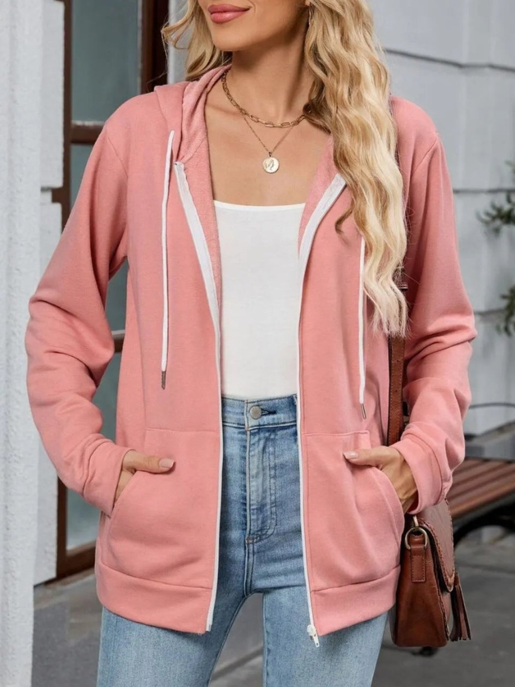 Vrouw draagt open roze capuchonvest met witte koorden, handen in de steekzakken | Boutique Moda