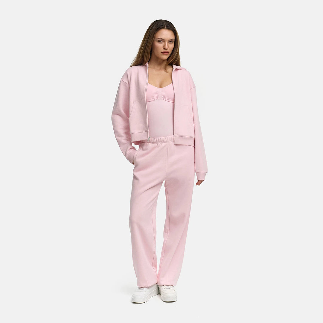 Vrouw draagt een lichtroze capuchonvest open over een roze topje met een bijpassende broek | Boutique Moda