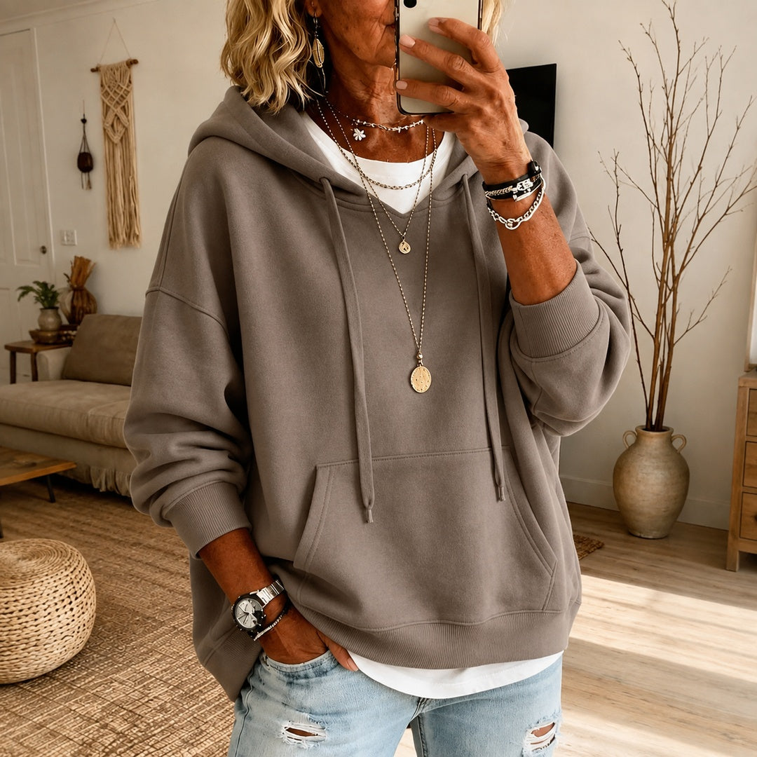 Vrouw in een taupe oversized trui met verlaagde schouders en een gescheurde jeans | Boutique Moda