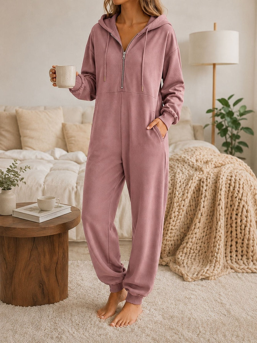 Onesie met capuchon in roze met halve rits en zakken opzij, vooraanzicht in de slaapkamer