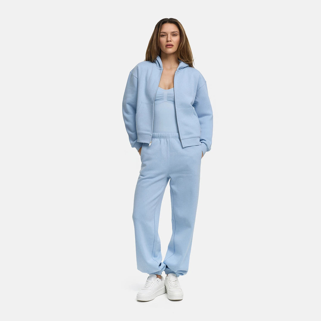 Vrouw draagt een lichtblauw capuchonvest met doorlopende rits over een lichtblauw topje | Boutique Moda