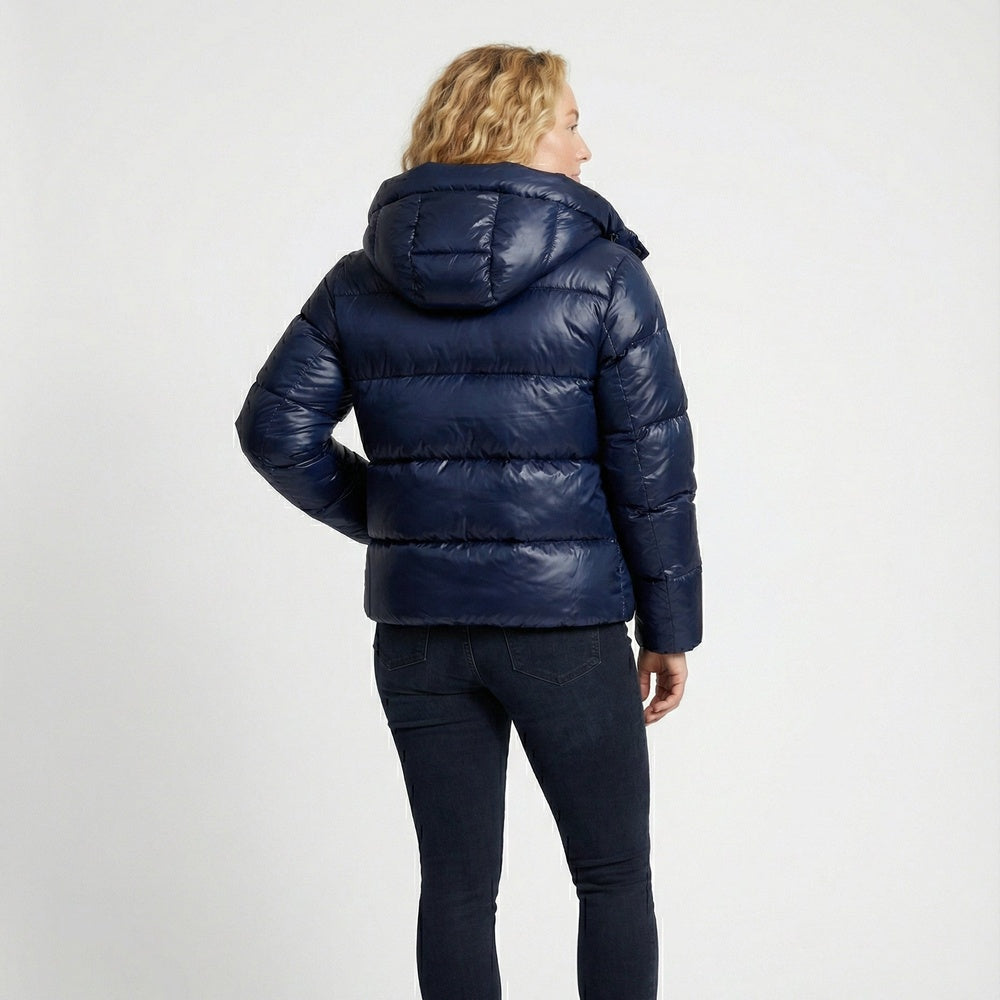 Donkerblauwe glanzende pufferjas met capuchon, gedragen door vrouw van achteren | Boutique Moda