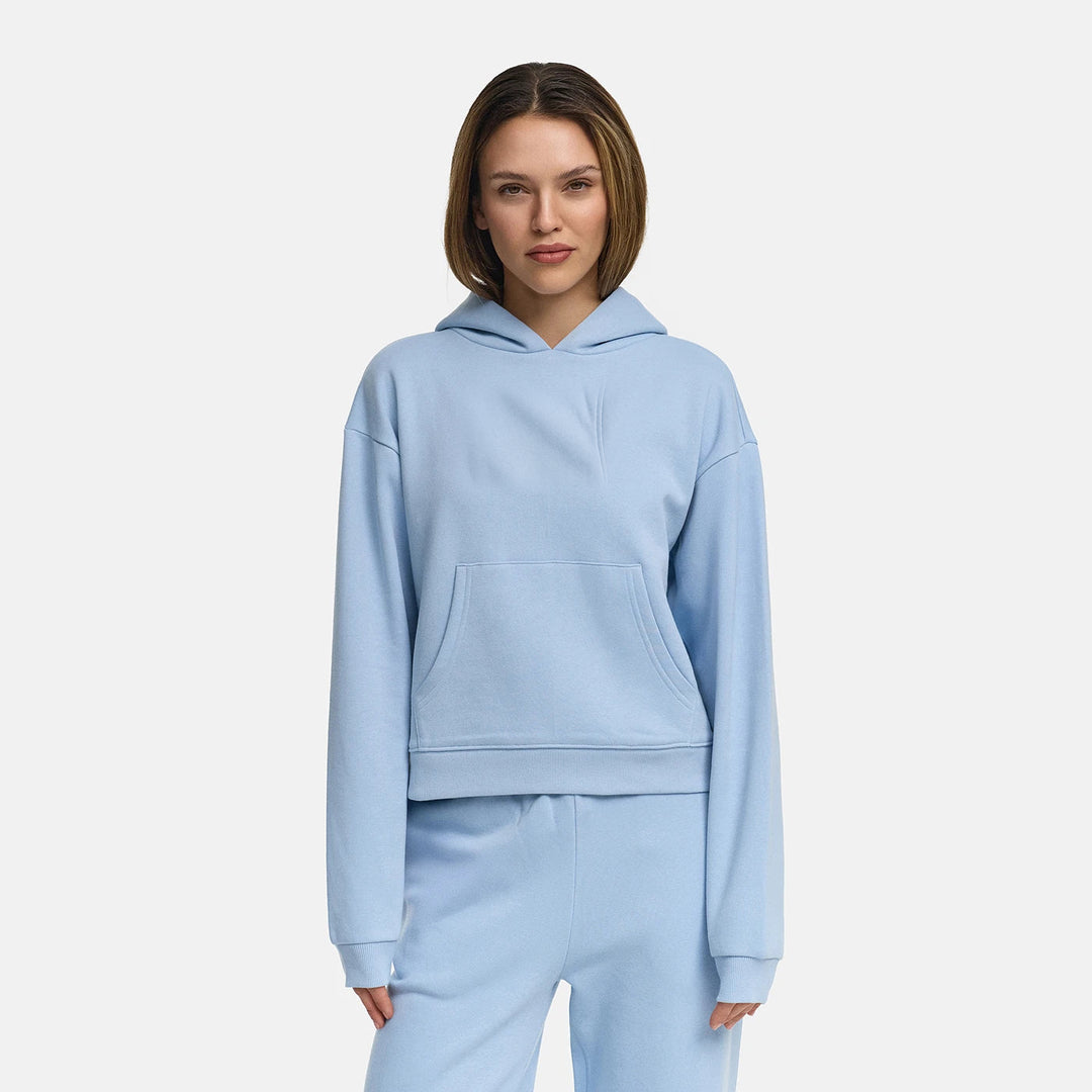 Vrouw in een lichtblauwe sweater met capuchon en geribde zoomband, vooraanzicht | Boutique Moda