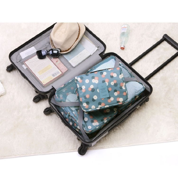 Blauwe toilettas met bloemenprint, plat liggend open in reiskoffer | Boutique Moda