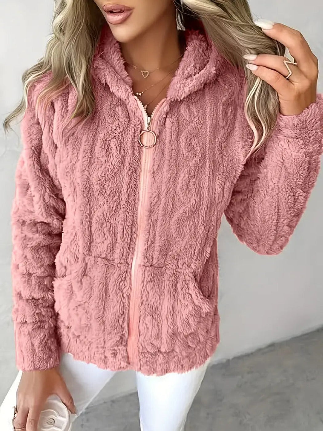 Vrouw draagt een roze teddyvest met ringtrekker en capuchon, hand in het haar | Boutique Moda