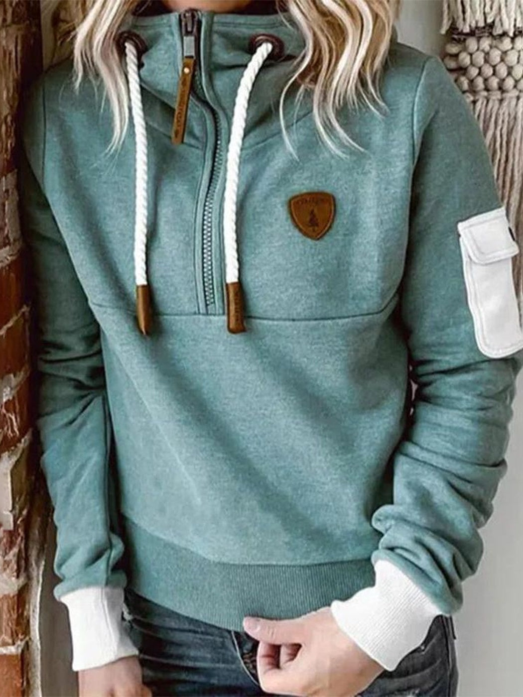 Mintgroene hoodie met kleine bruine patch op de borst en geribde zoom, vooraanzicht | Boutique Moda