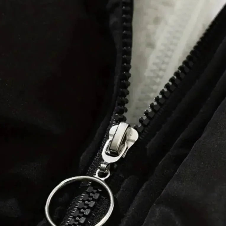 Pufferjas met capuchon en teddyvoering in zwart, close-up van de rits