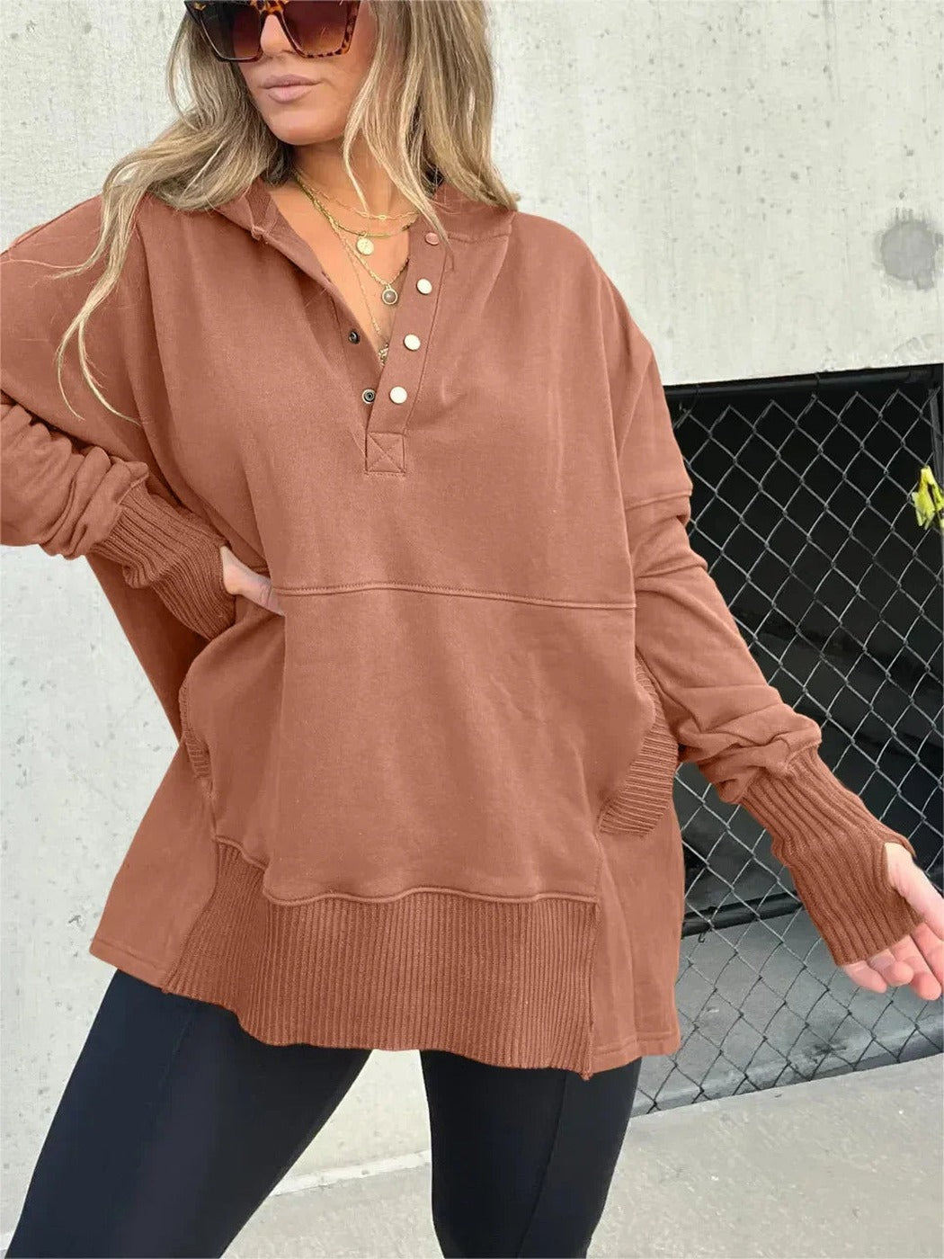 Vrouw in roestbruine oversized trui met knoopsluiting en kangoeroezak | Boutique Moda