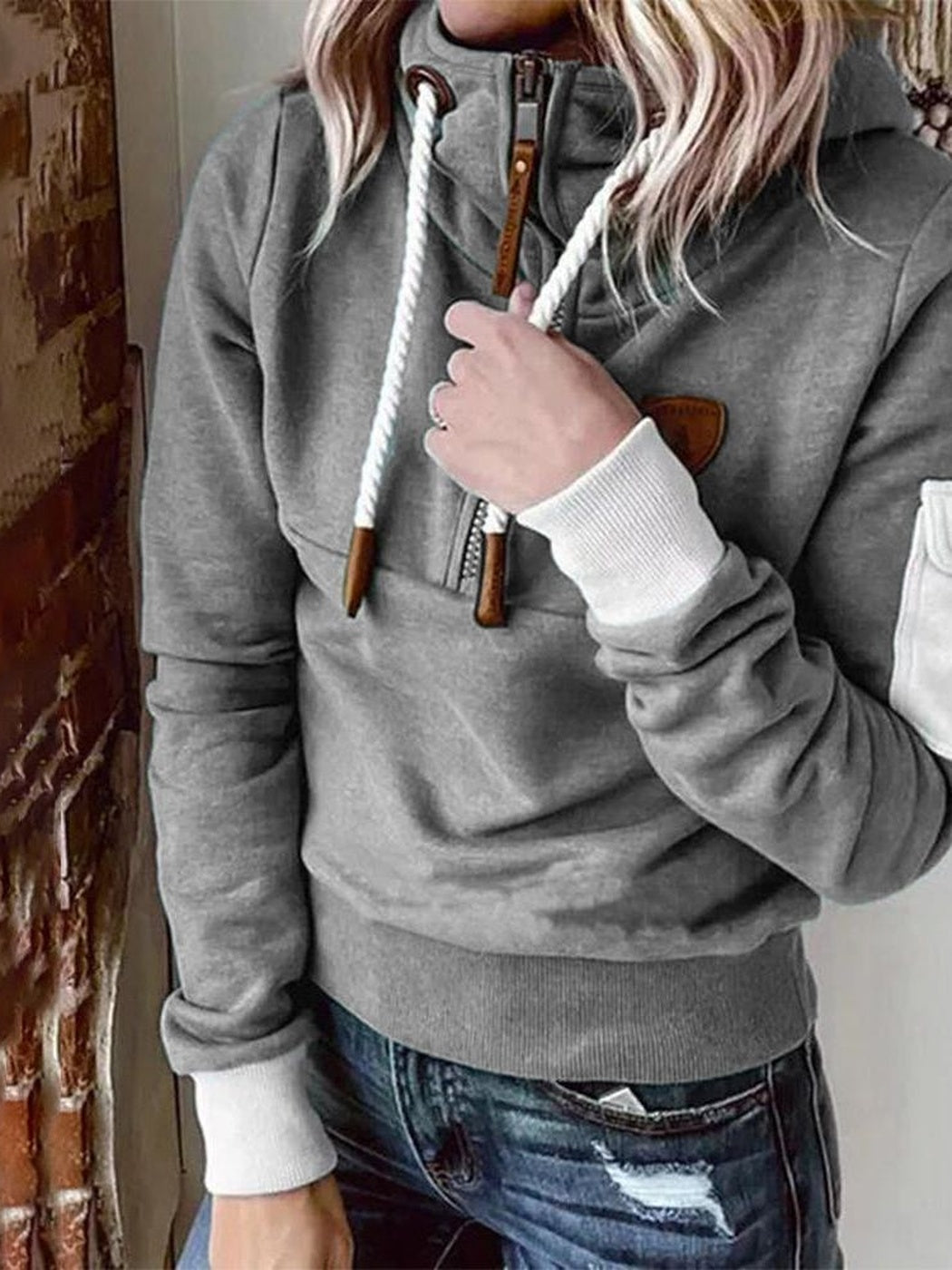 Vrouw in een grijze hoodie die een koord vasthoudt, met witte geribde boorden | Boutique Moda